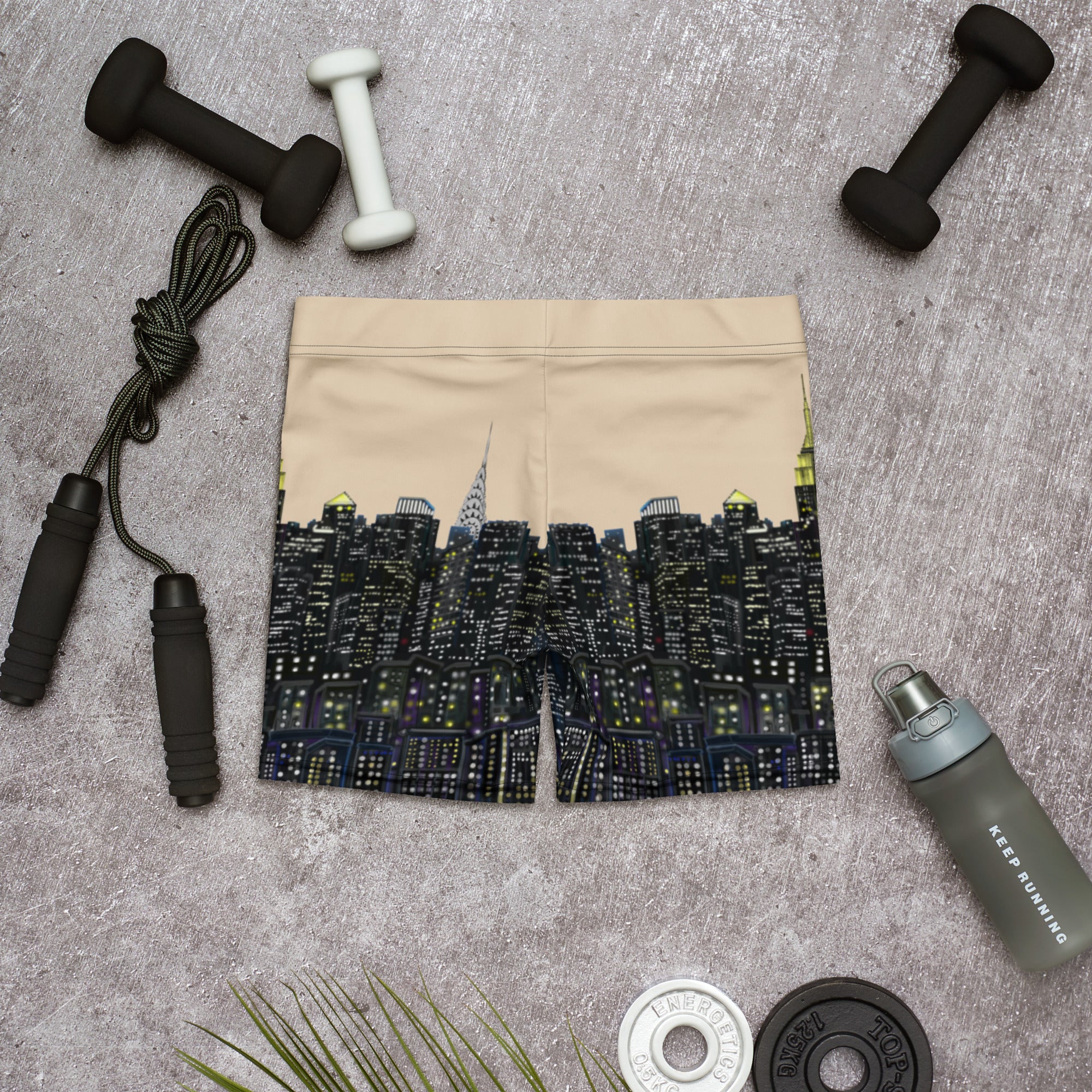 Beige drawstring bag with cityscape design on a gray surface with fitness equipment.