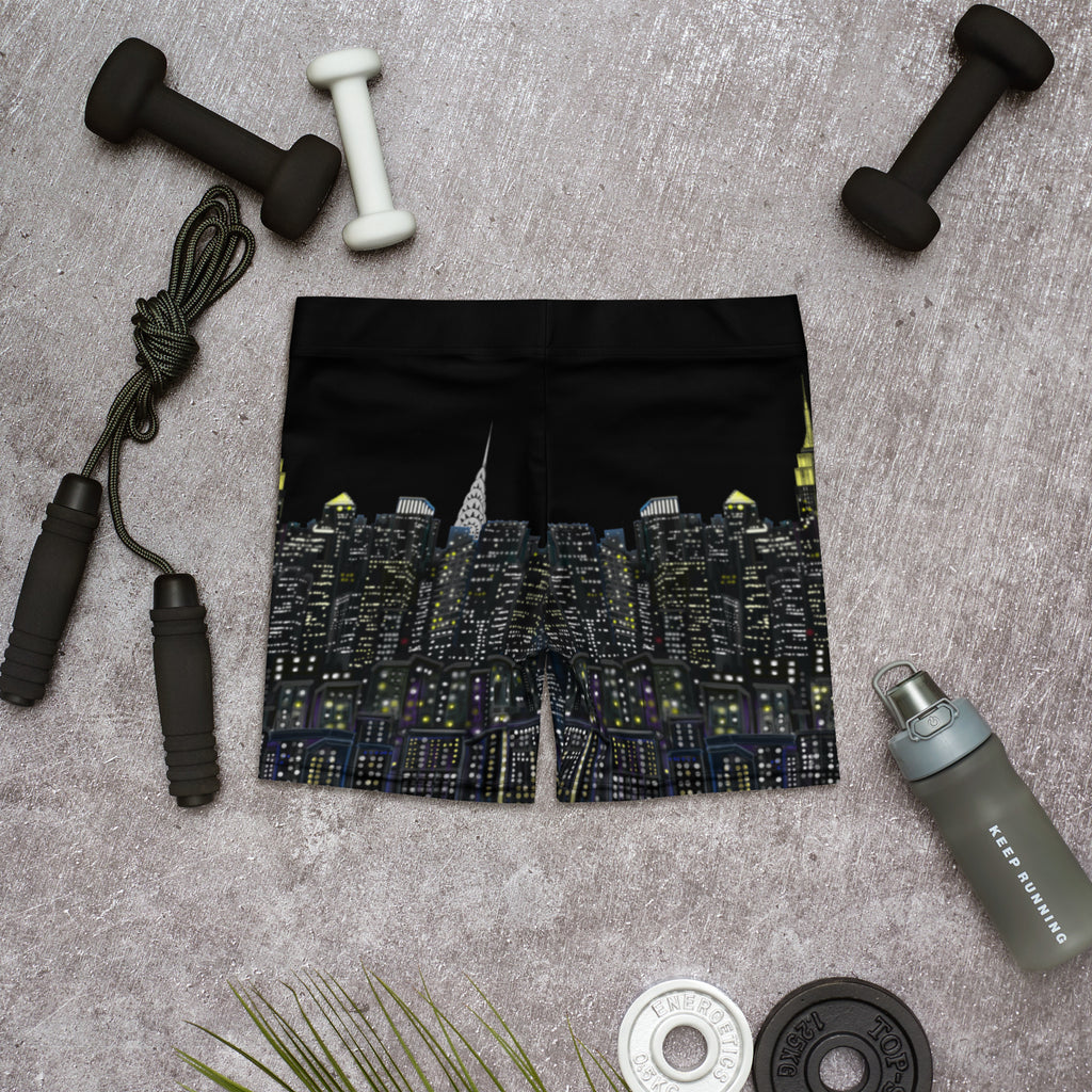 Black shorts with cityscape Loria NYC Art design on a gray surface with fitness equipment.