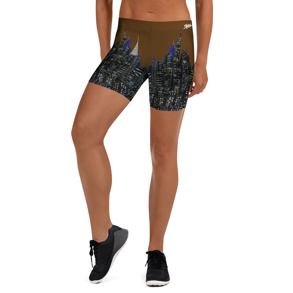 Person wearing brown Loria NYC Art athletic shorts with cityscape design on a white background