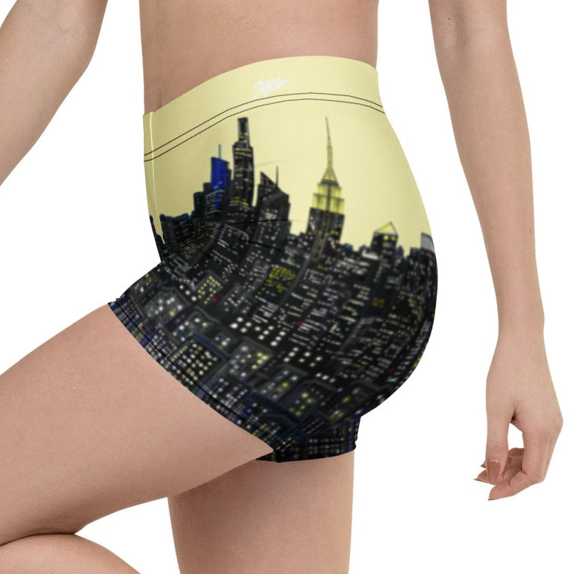 Person wearing black shorts with a cityscape design and black sneakers on a white background
