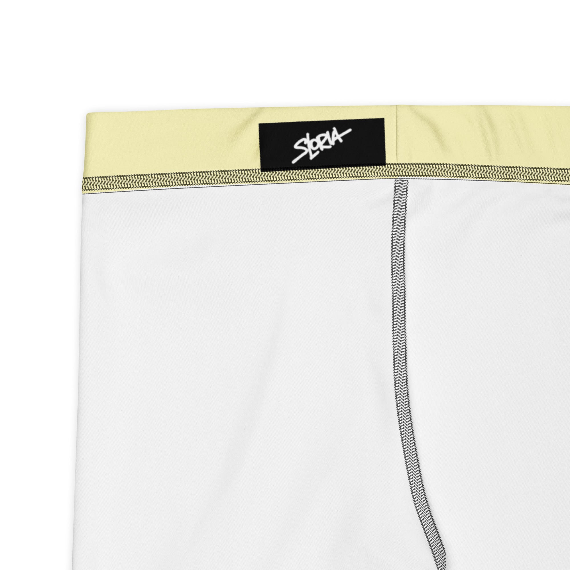Athletic shorts  with a yellow waistband and black brand label on a white background 