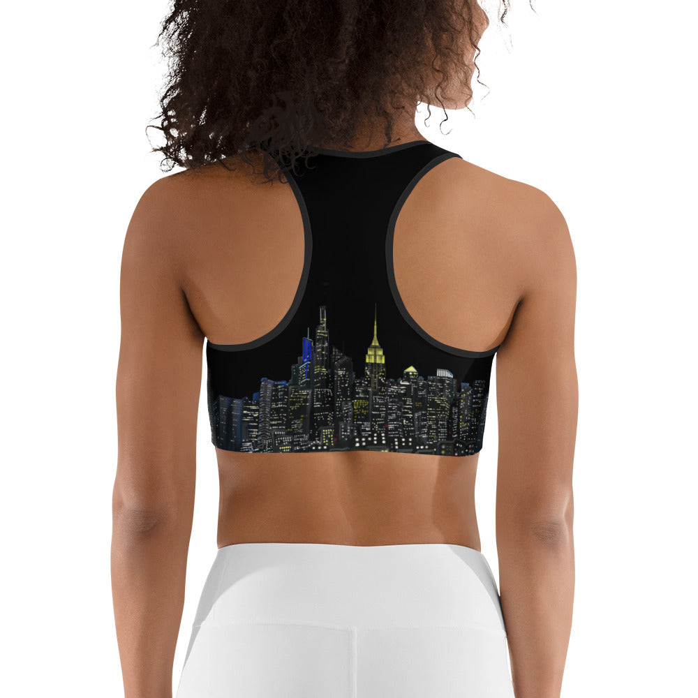 Woman wearing a black sports bra designed by Loria NYC Art with cityscape design and white leggings on a white background