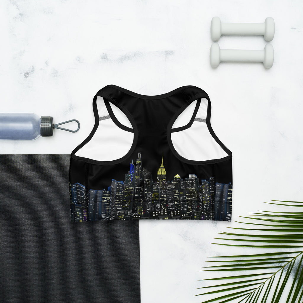 Back of Black sports bra with cityscape design on a white marble surface with fitness items.
