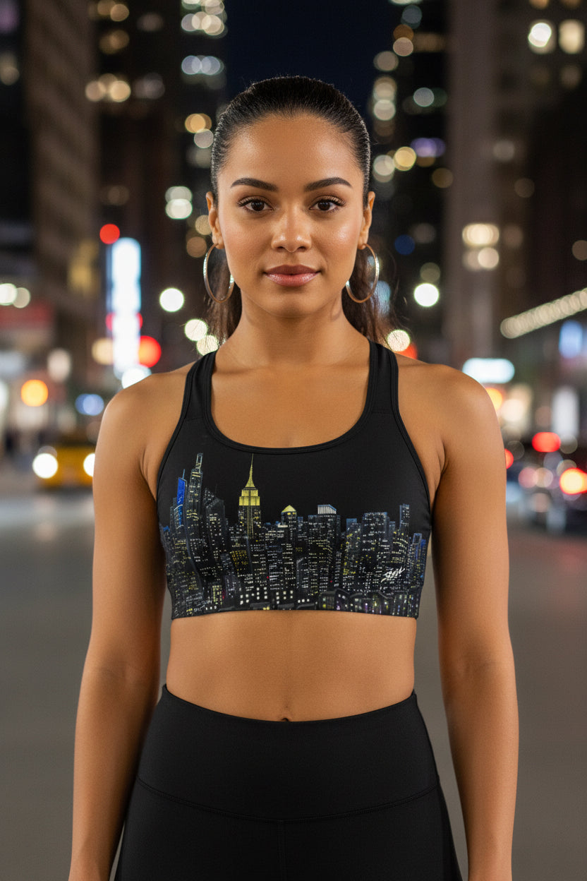 Woman wearing a black sports bra designed by Loria NYC Art with cityscape design and white leggings on a urban background