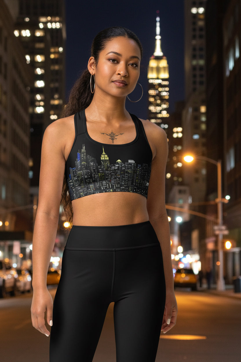 Woman wearing a black sports bra designed by Loria NYC Art with cityscape design and beige leggings on a urban background