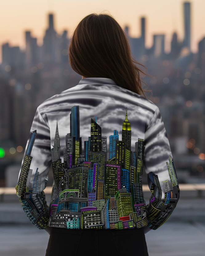 Person wearing a jacket with a cityscape designed by Loria NYC Art standing on a rooftop with a city skyline in the background.