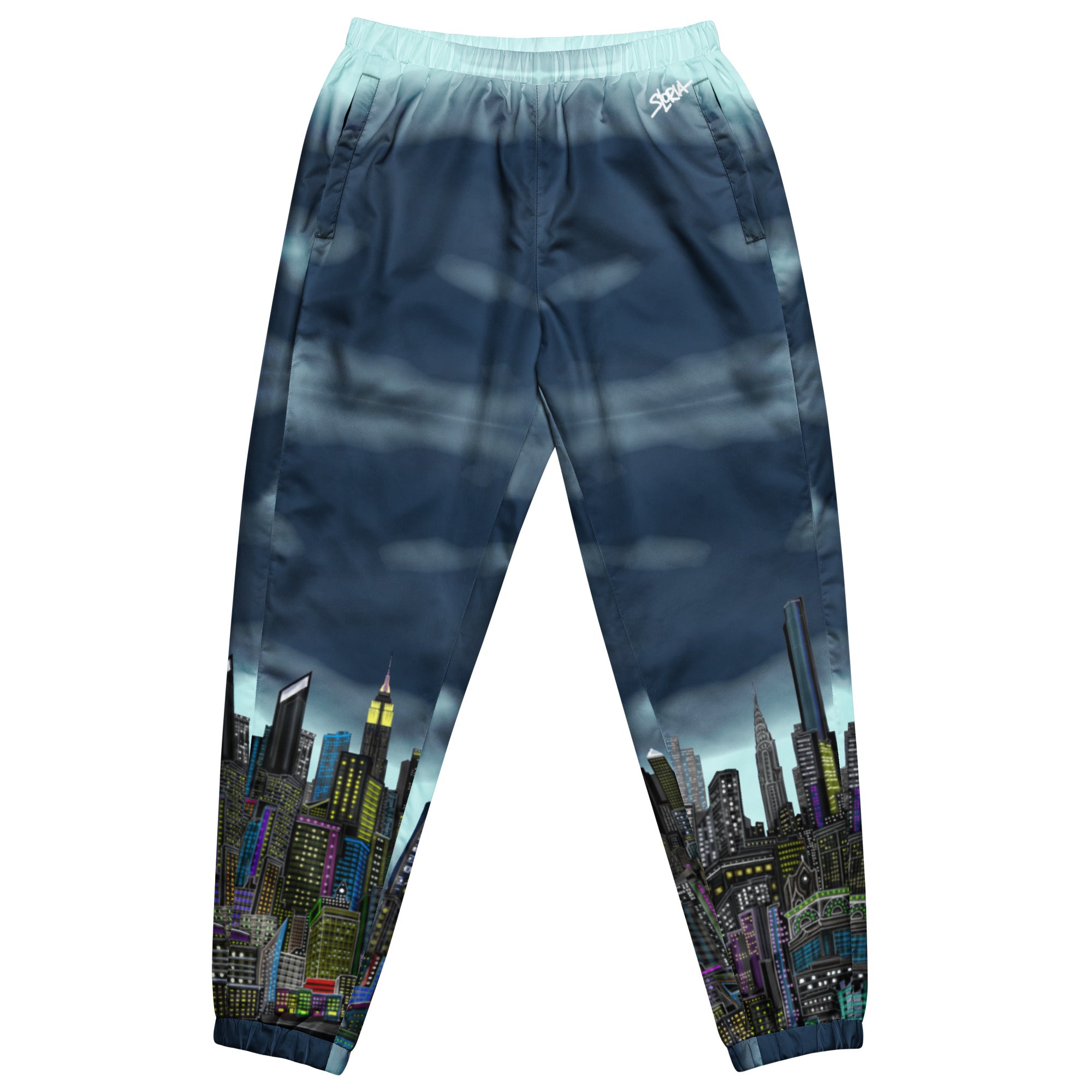 View of blue track pants with cityscape design by Loria NYC Art on a white background