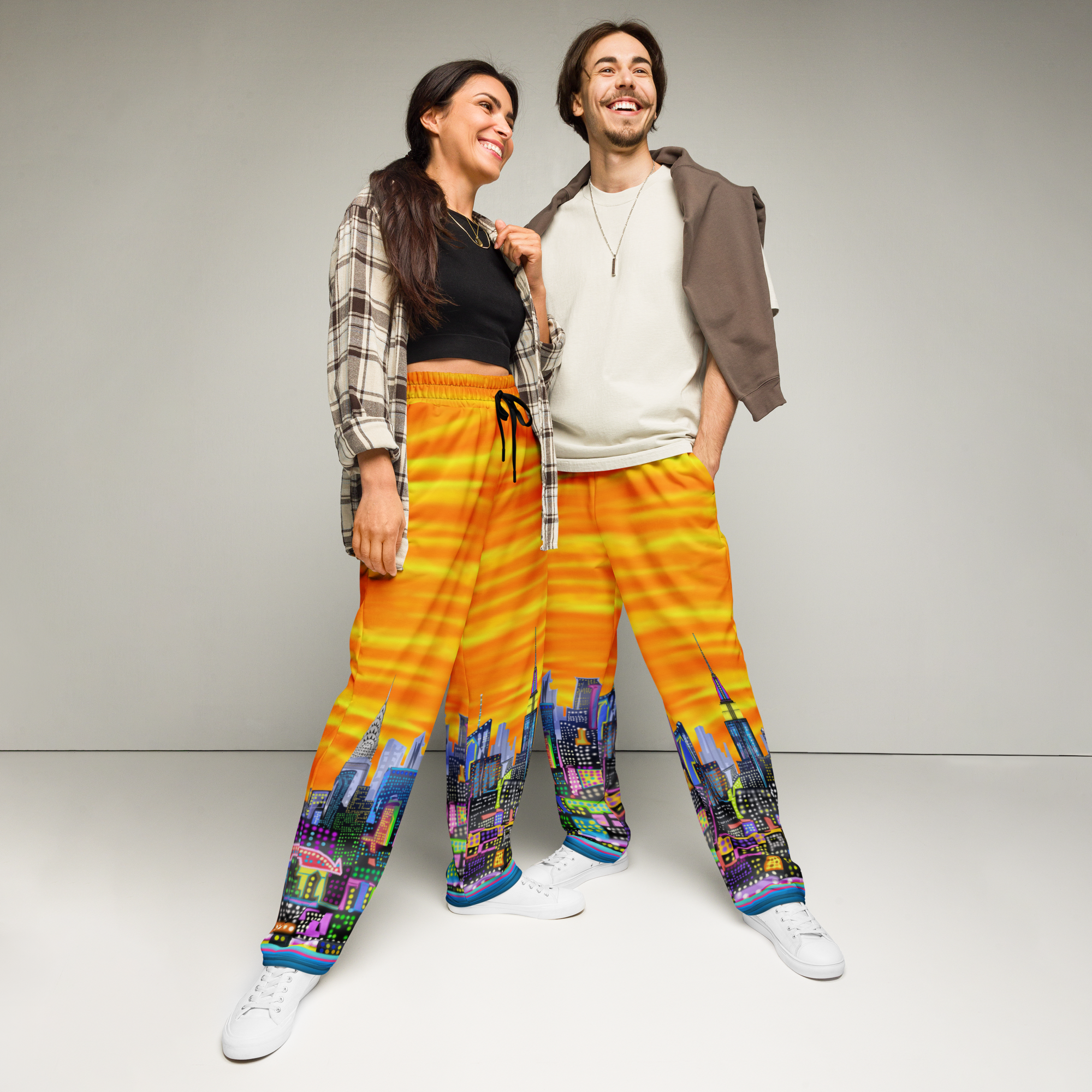 Two people wearing colorful pants with Loria NYC Art cityscape design on a plain background