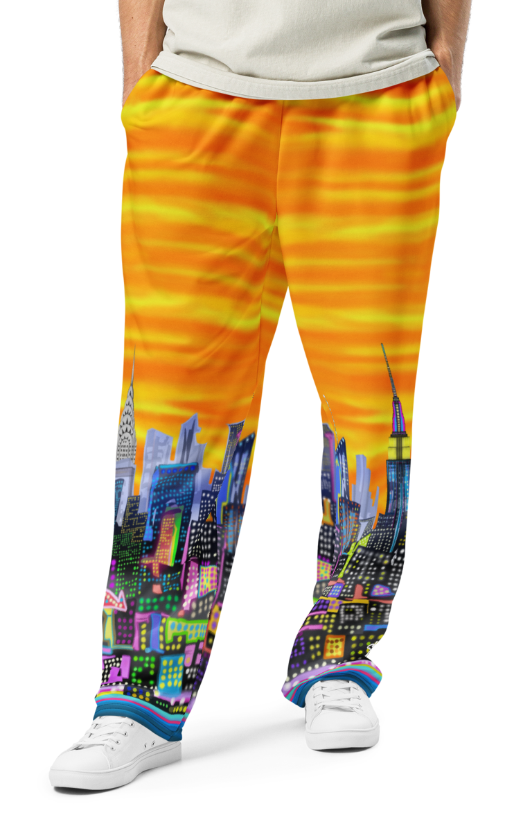 Person wearing a light gray t-shirt and colorful Loria NYC Art pants with cityscape design on a white background
