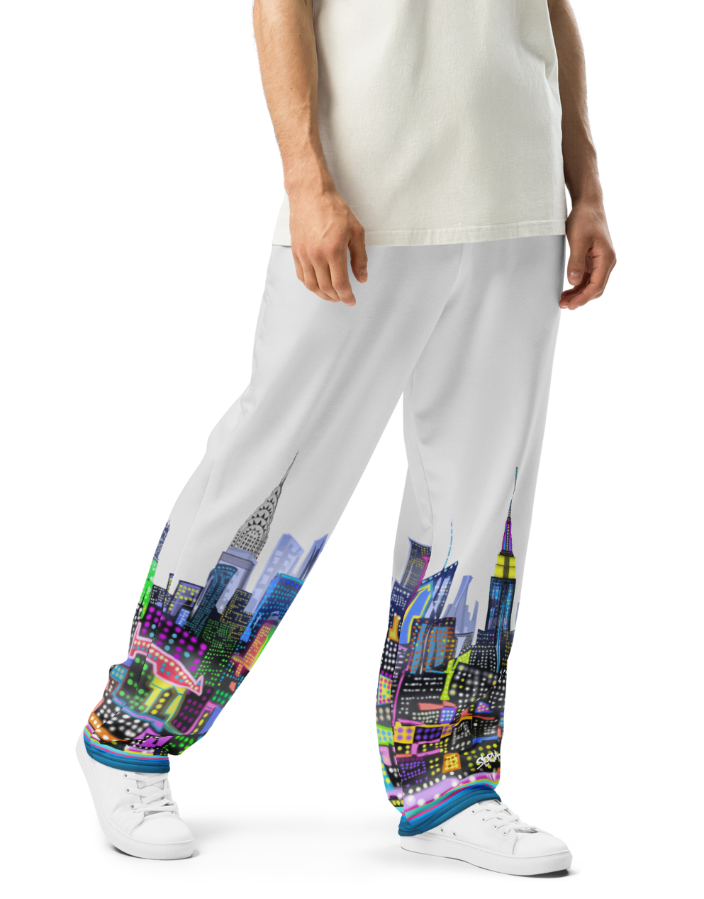 Person wearing a white t-shirt and colorful Loria NYC Art pants on a white background