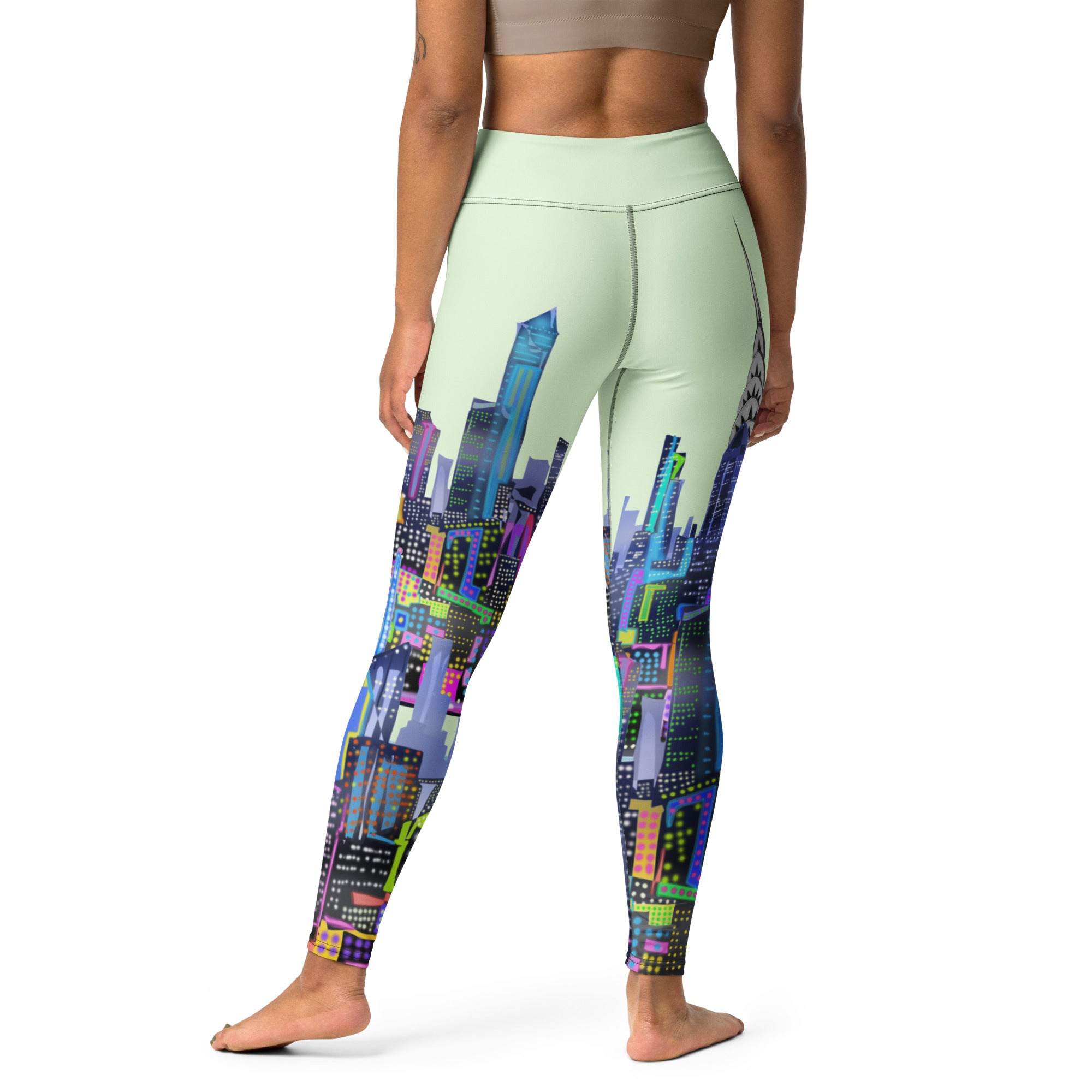 Person wearing light green Loria NYC Art leggings with colorful cityscape design on a white background