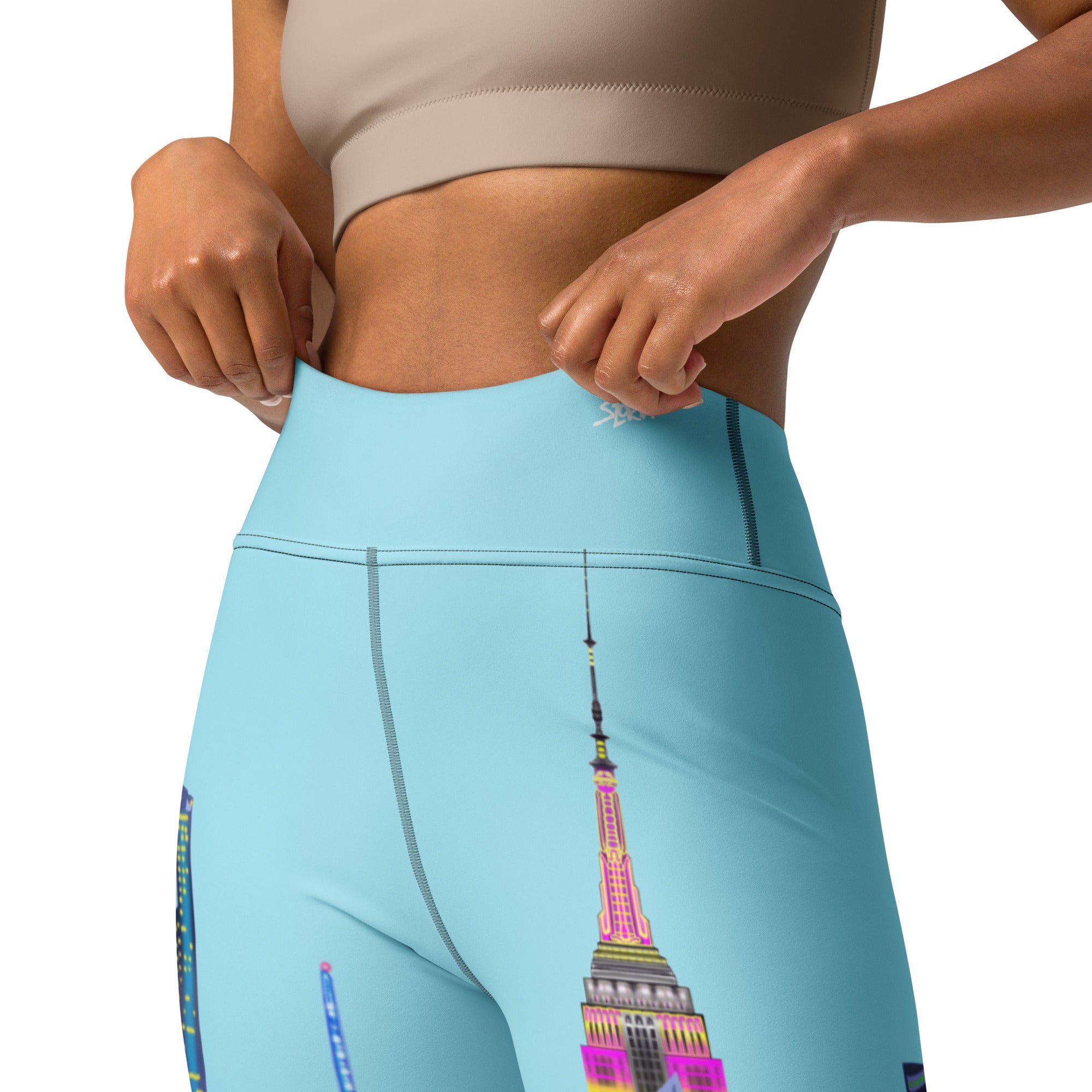 Light blue Loria NYC Art leggings with a colorful Empire State Building design worn by a person.