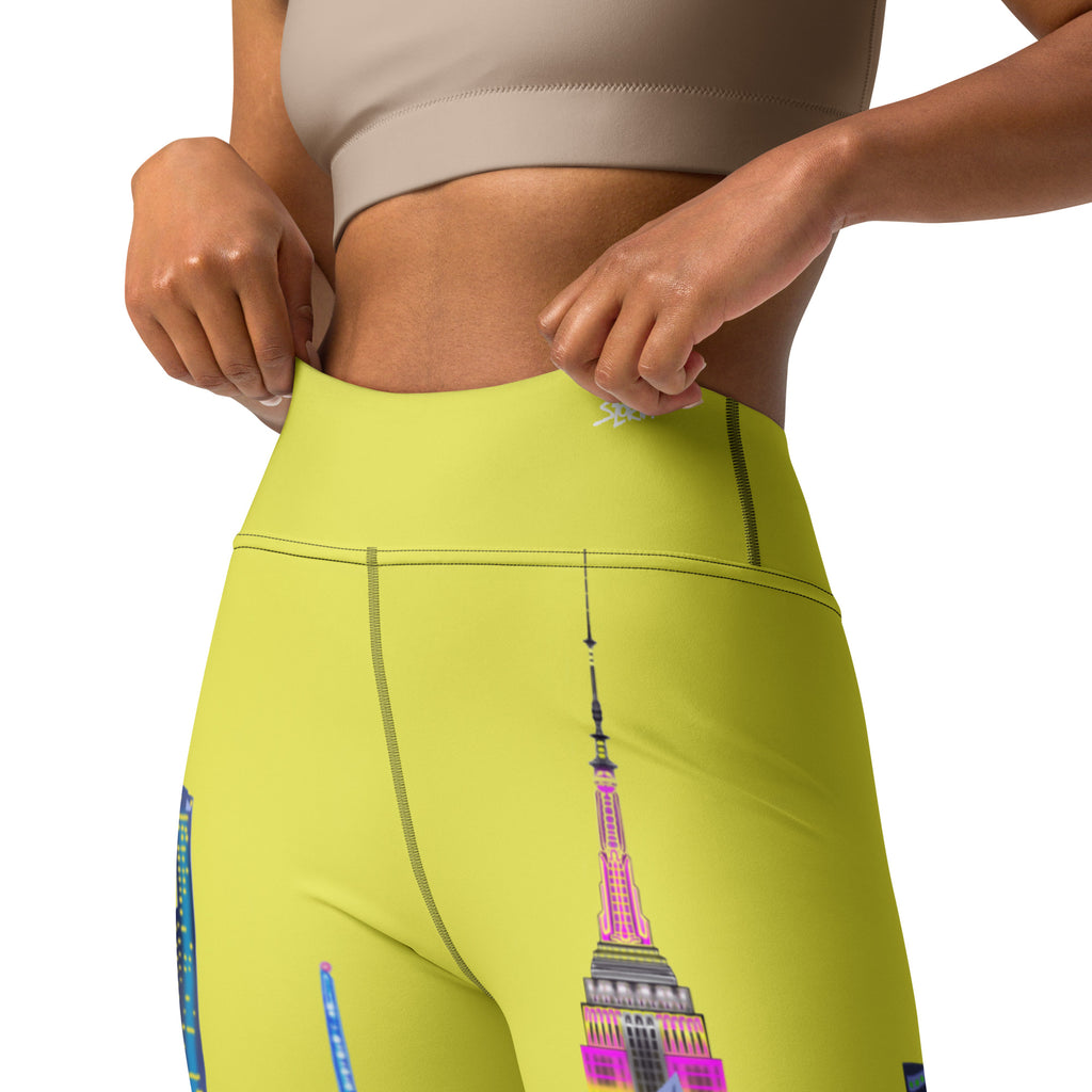 Person wearing bright yellow leggings with a colorful Loria NYC Art design on a white background