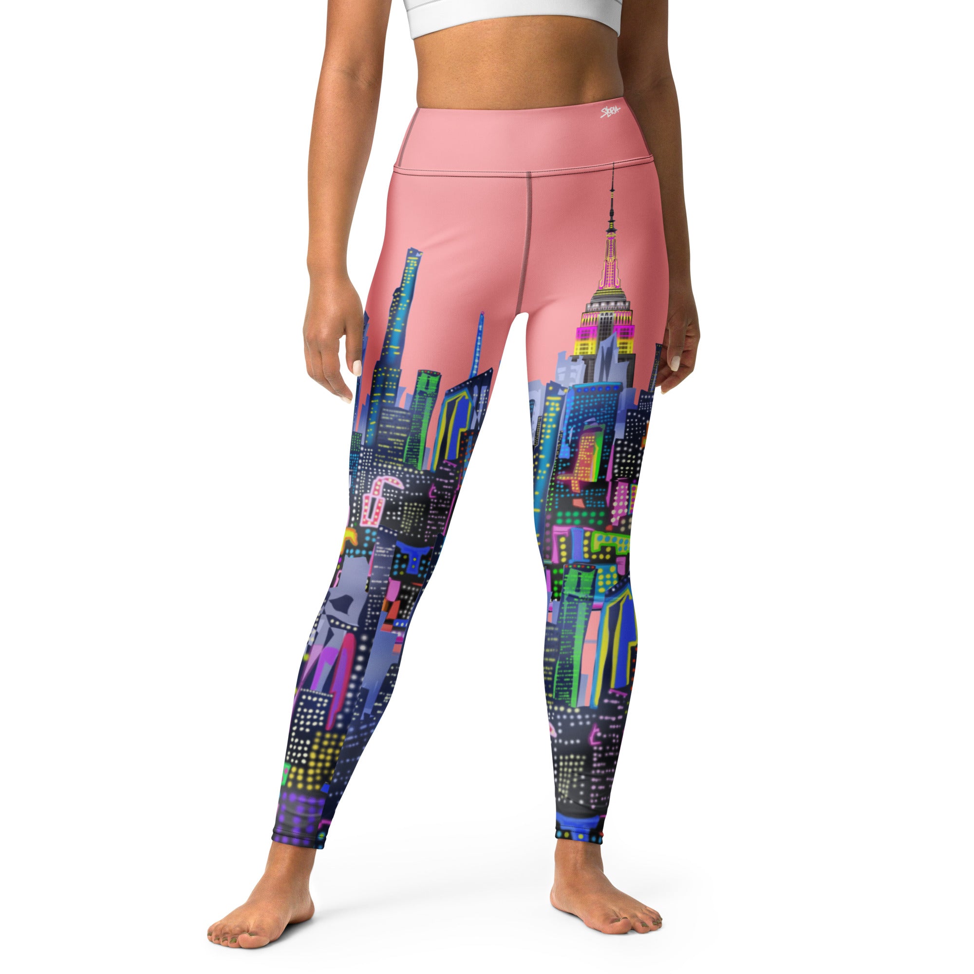 Person wearing pink leggings with a Loria NYC Art colorful cityscape design on a white background