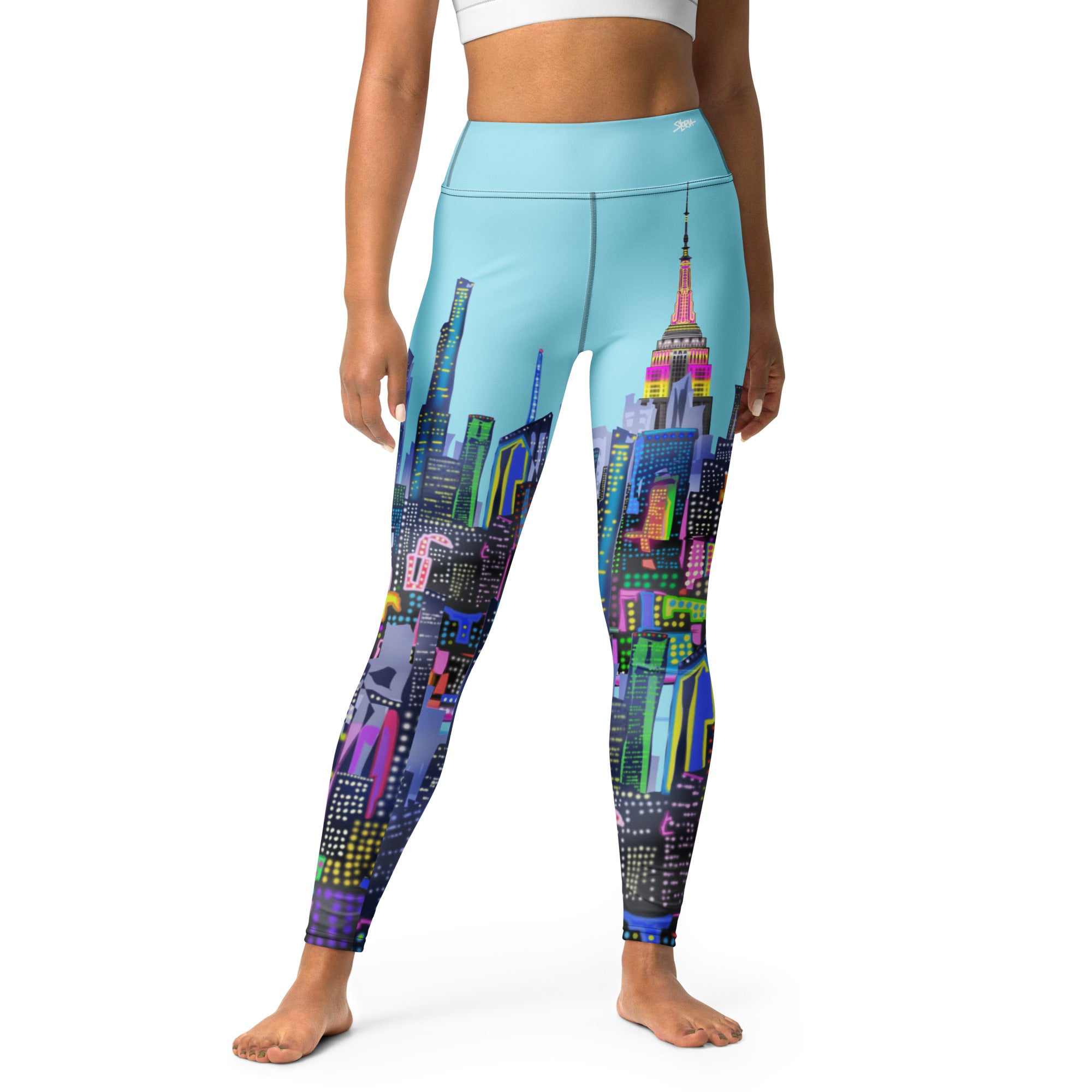 Girl wearing blue Loria NYC Art Leggings with cityscape design worn by a person on a white background