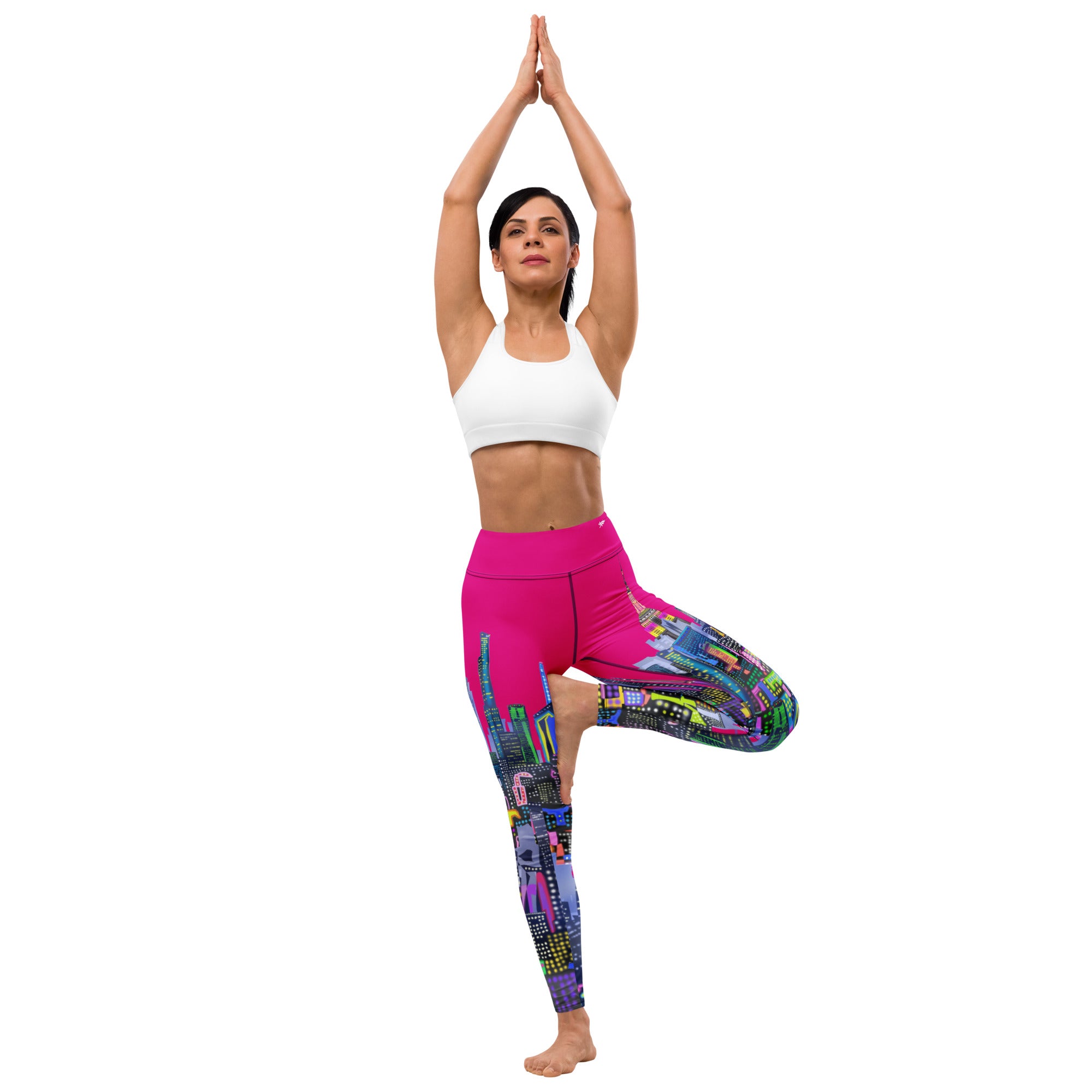 Woman in white sports bra and colorful yoga Loria NYC Art pants posing against a white background