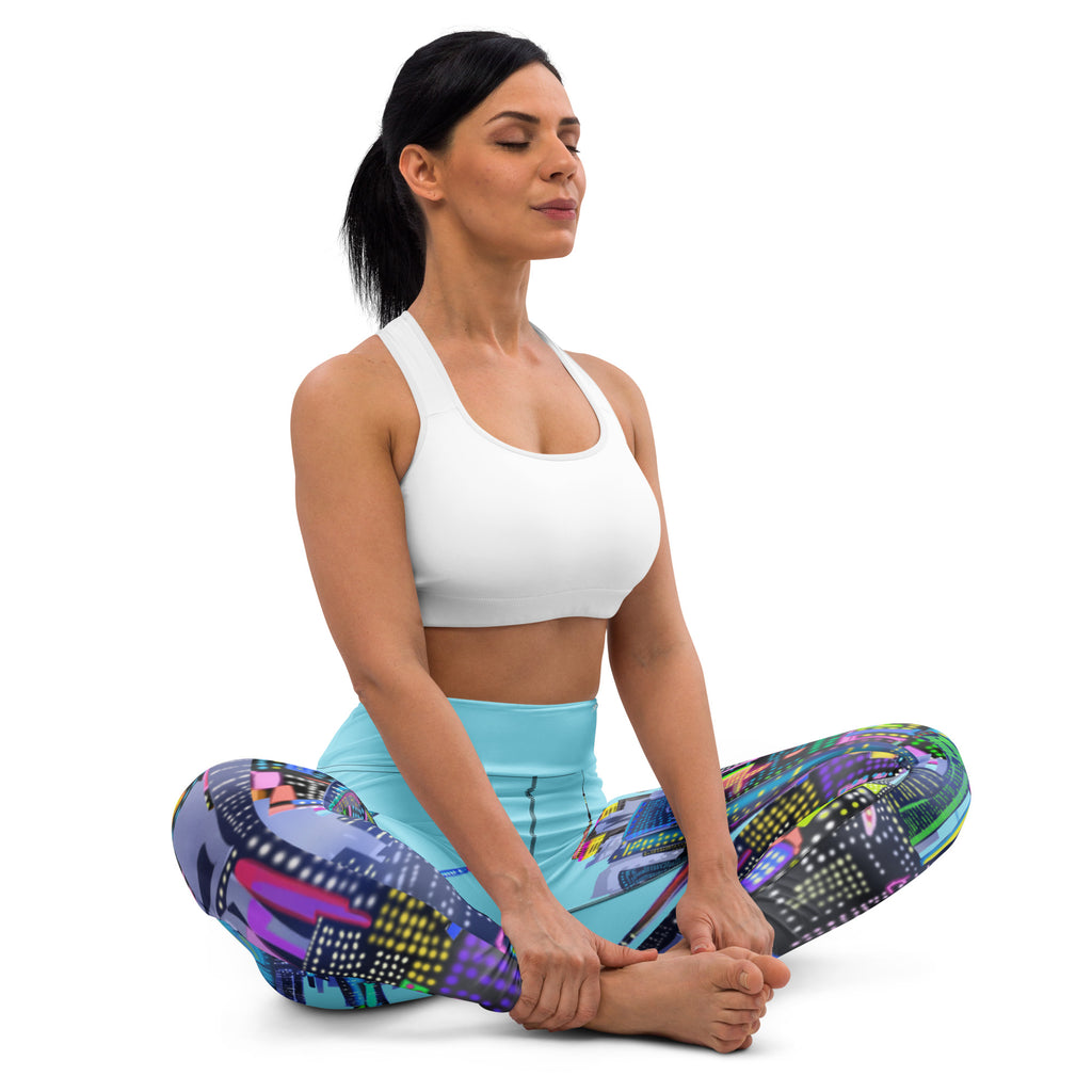 Woman sitting in a yoga pose wearing colorful Loria NYC Art leggings and a white sports bra on a white background