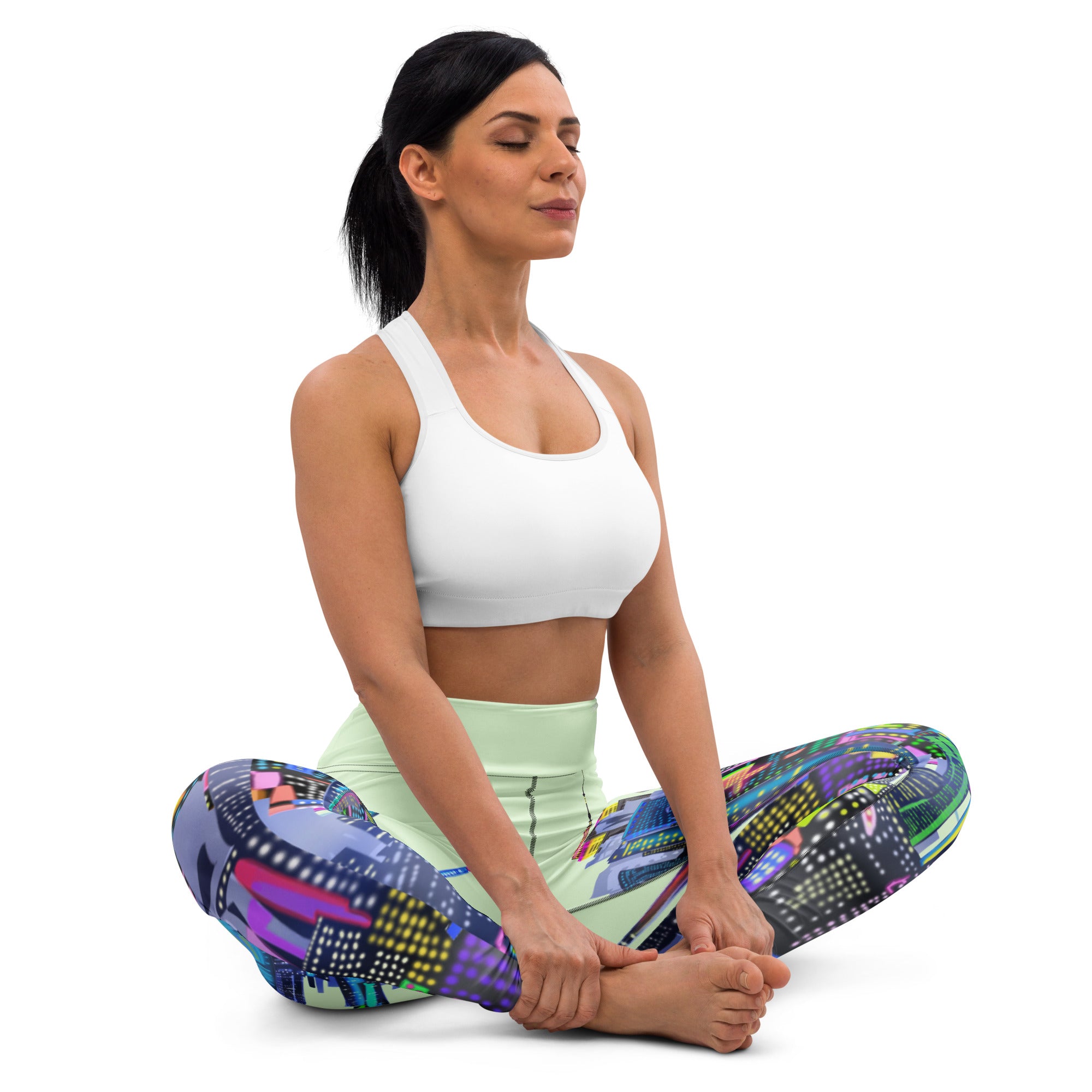 Woman in a yoga pose wearing Loria NYC Art colorful leggings and a white sports bra on a white background