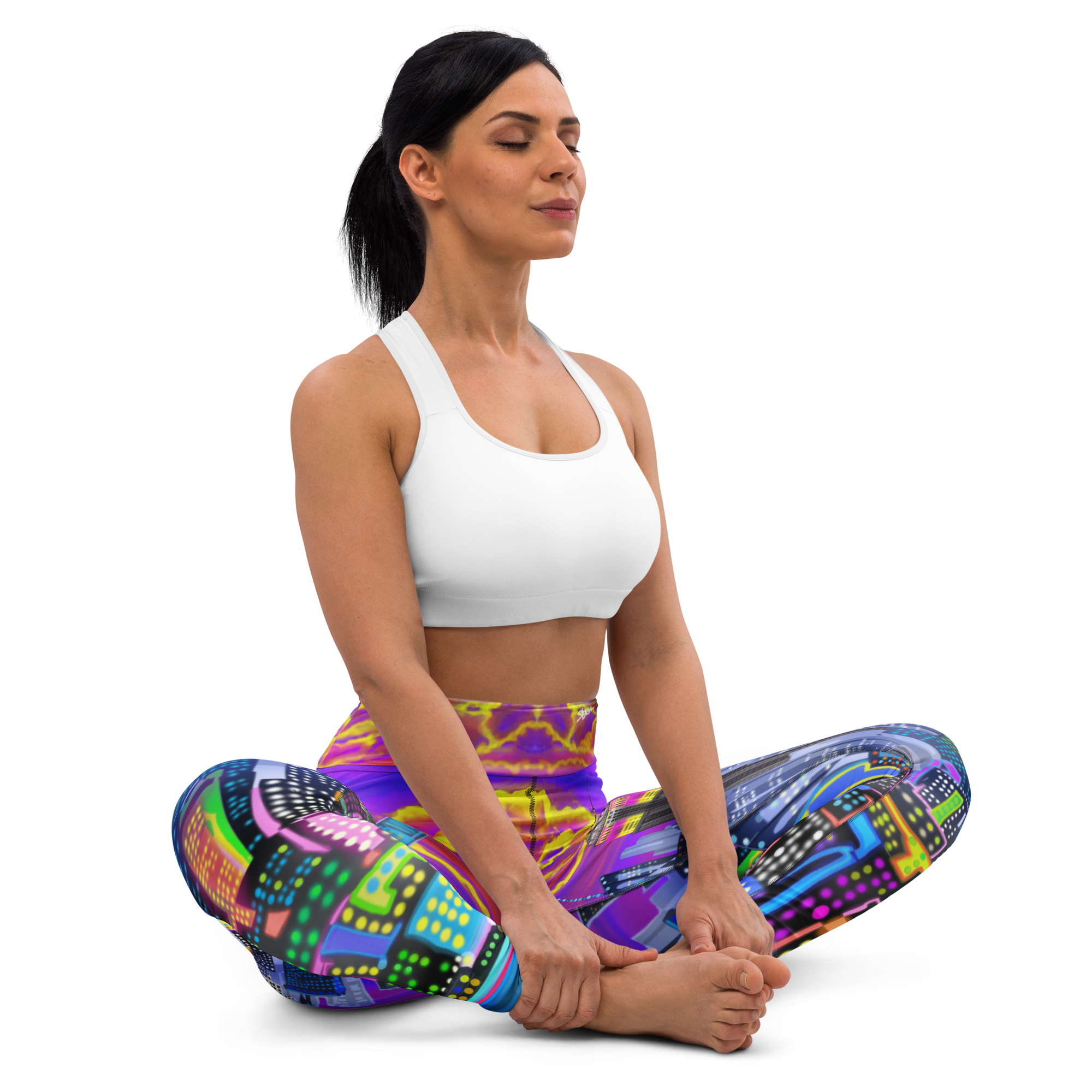 Woman in a white sports bra and Loria NYC Art colorful yoga pants sitting in a yoga pose on a white background