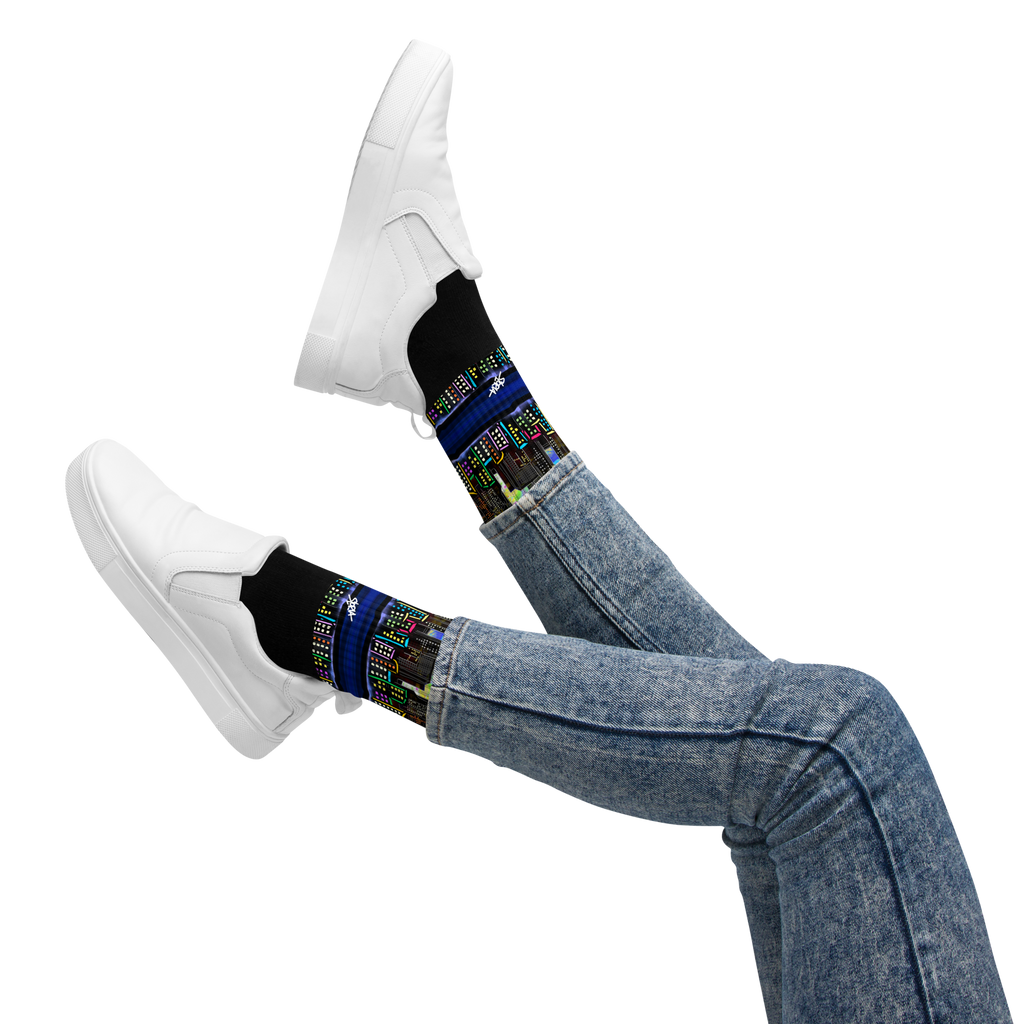 Person wearing Loria NYC Art black socks with colorful patterns and white sneakers on a white background