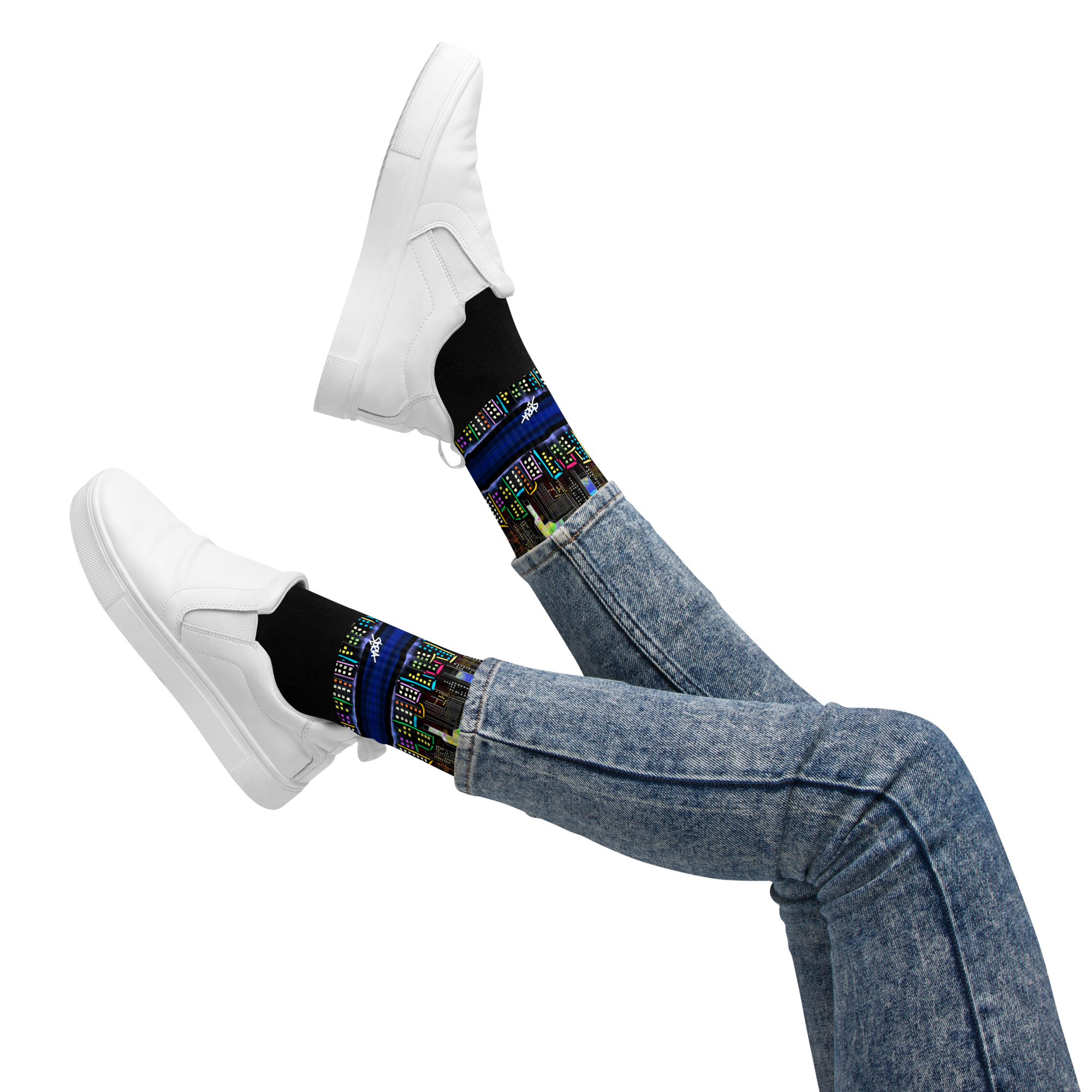 Person wearing Loria NYC Art black socks with colorful patterns and white sneakers on a white background