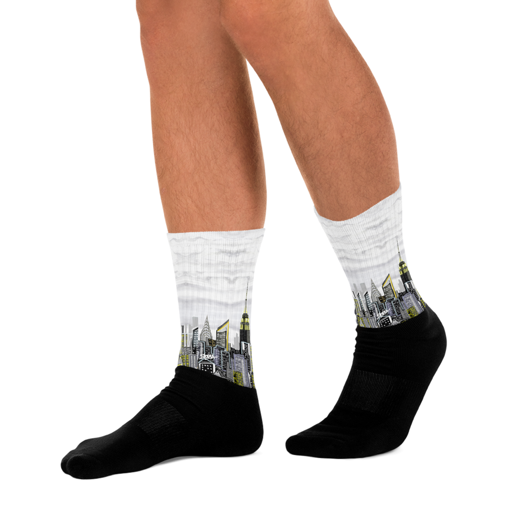 Black Loria NYC Art socks with cityscape design worn by a person on a white background
