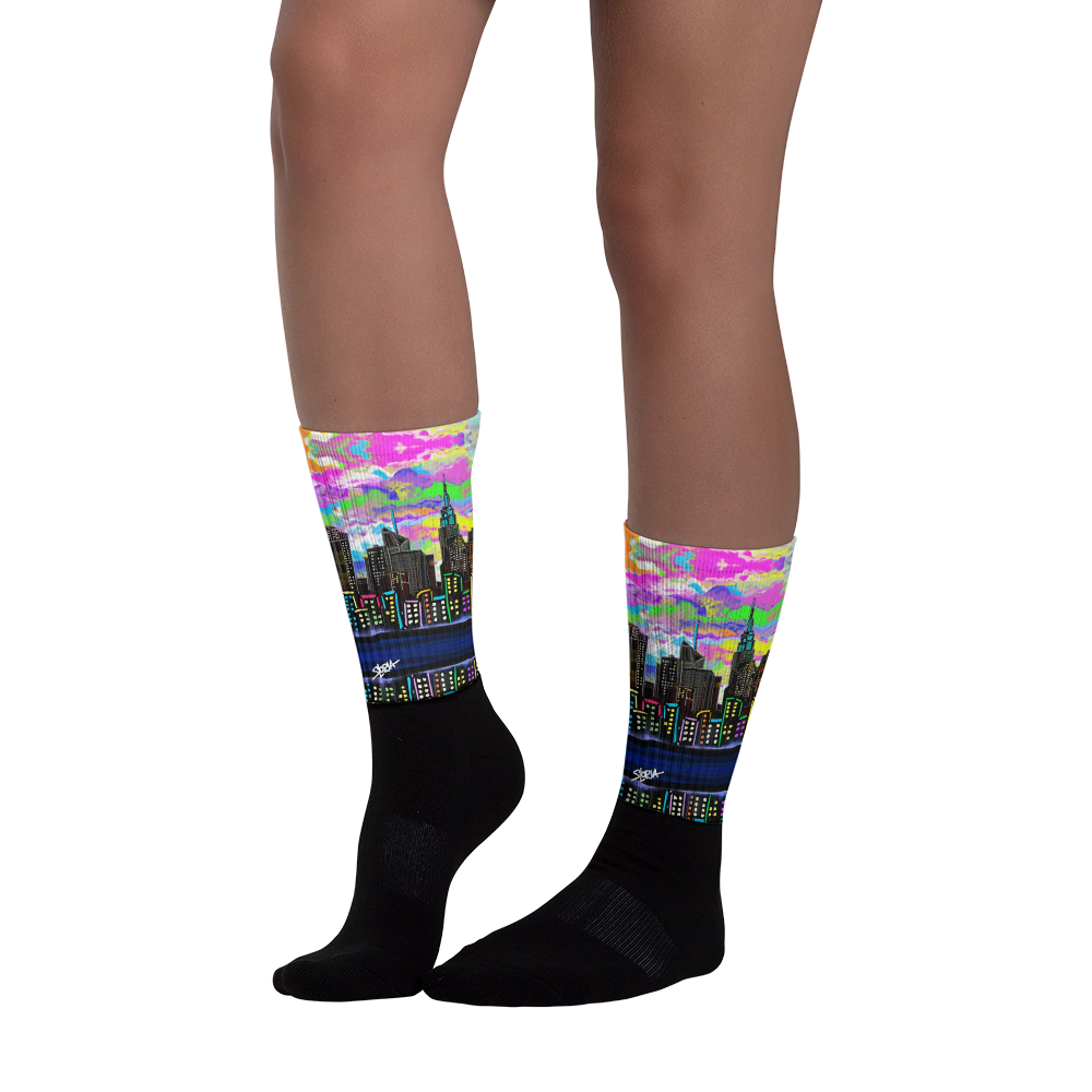 Colorful cityscape Loria NYC Art socks worn by a person on a white background