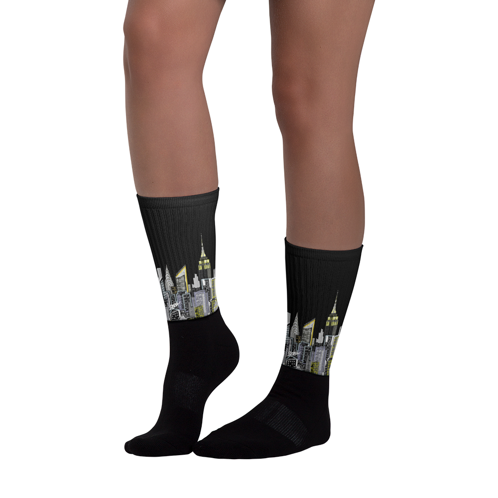 Black socks with cityscape Loria NYC Art design worn by a person on a white background