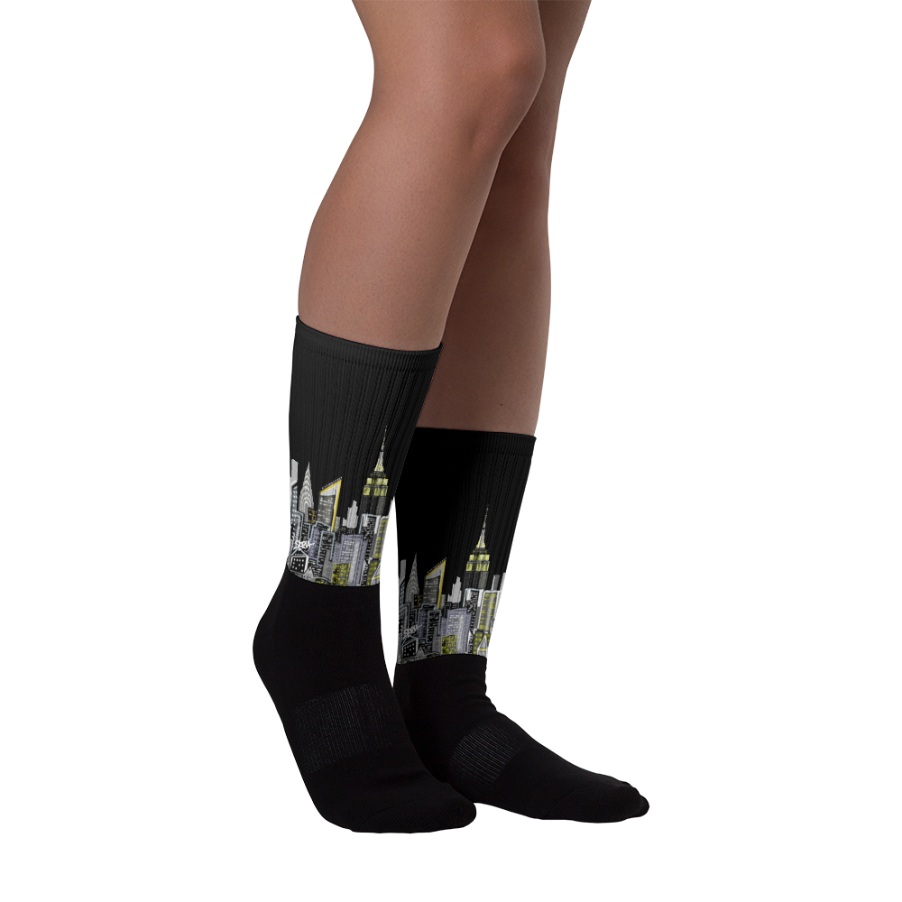 Black socks with cityscape Loria NYC Art design worn by a person on a white background