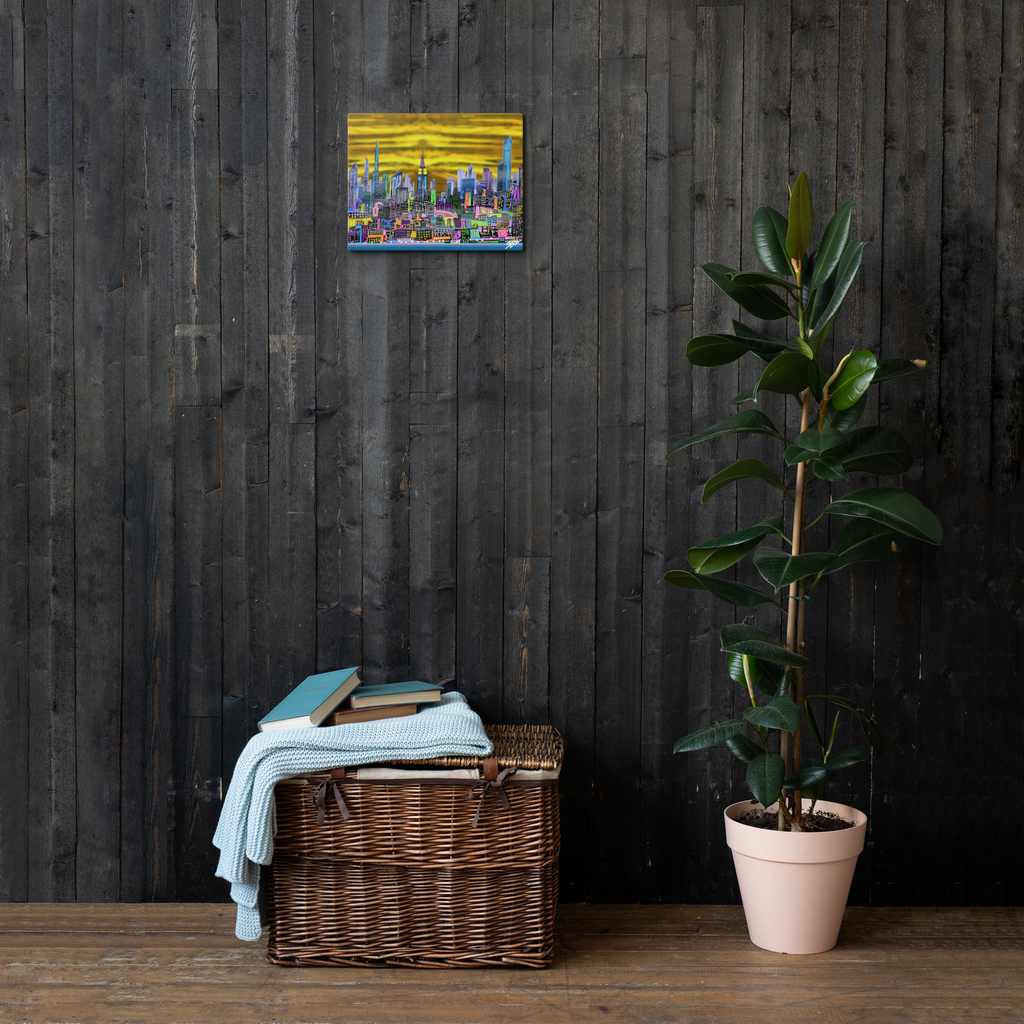 Wicker basket with folded clothes against a dark wooden wall with a small colorful 11’’ x 14’’ Canvas  Loria NYC Art painting, next to a potted plant.