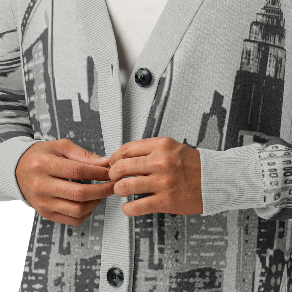 Person wearing a cardigan with a cityscape Loria NYC Art, focusing on the hands and cardigan.