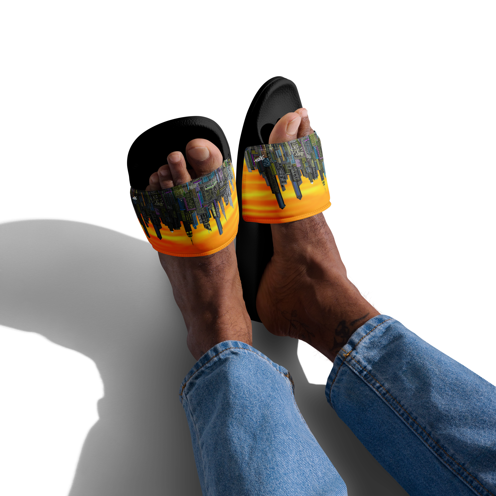 Person wearing black and orange slide sandals with a Loria NYC Art cityscape design on a white background