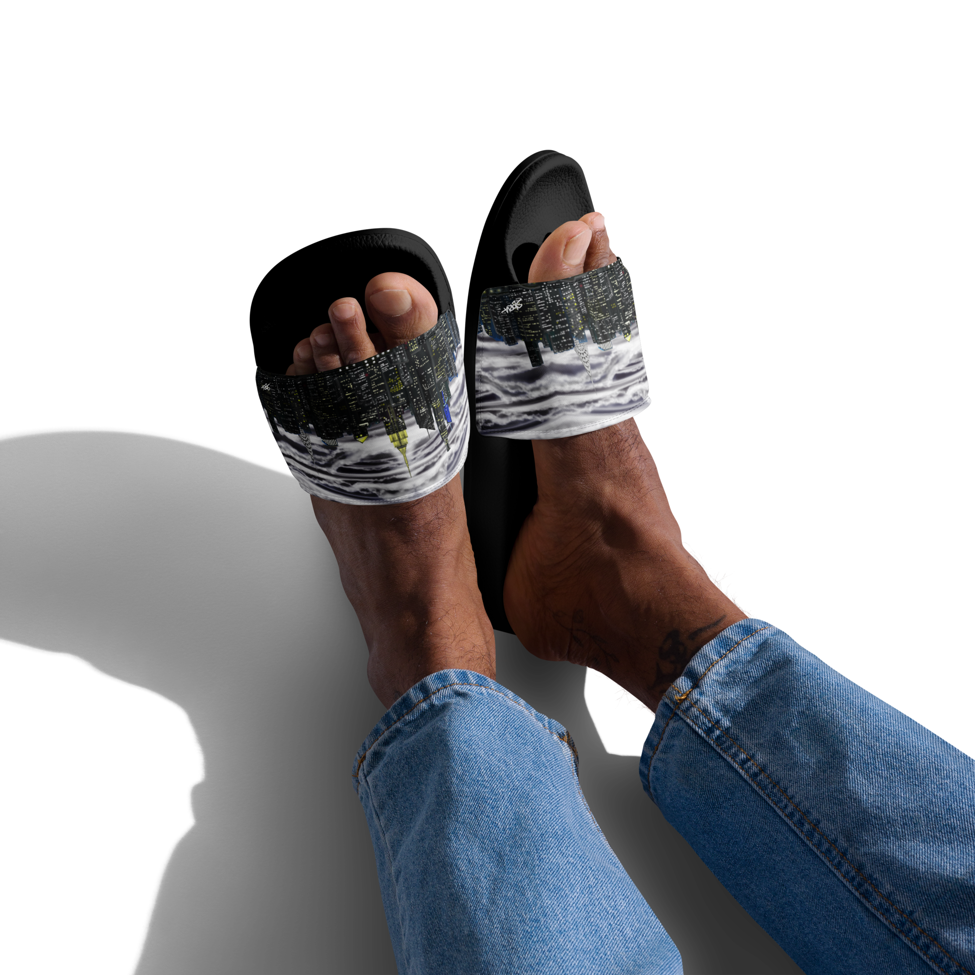 Black sandals with white Loria NYC Art worn by a person on a white background
