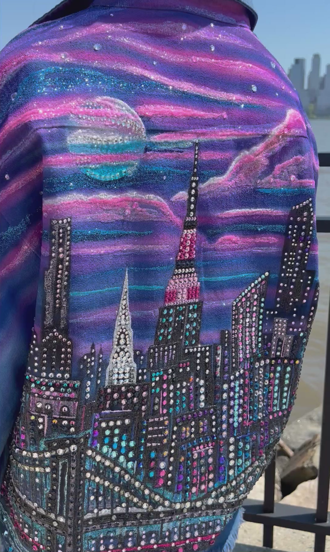 Colorful wearable Loria NYC Art jacket with crystals reflecting outside and city skyline in the background.