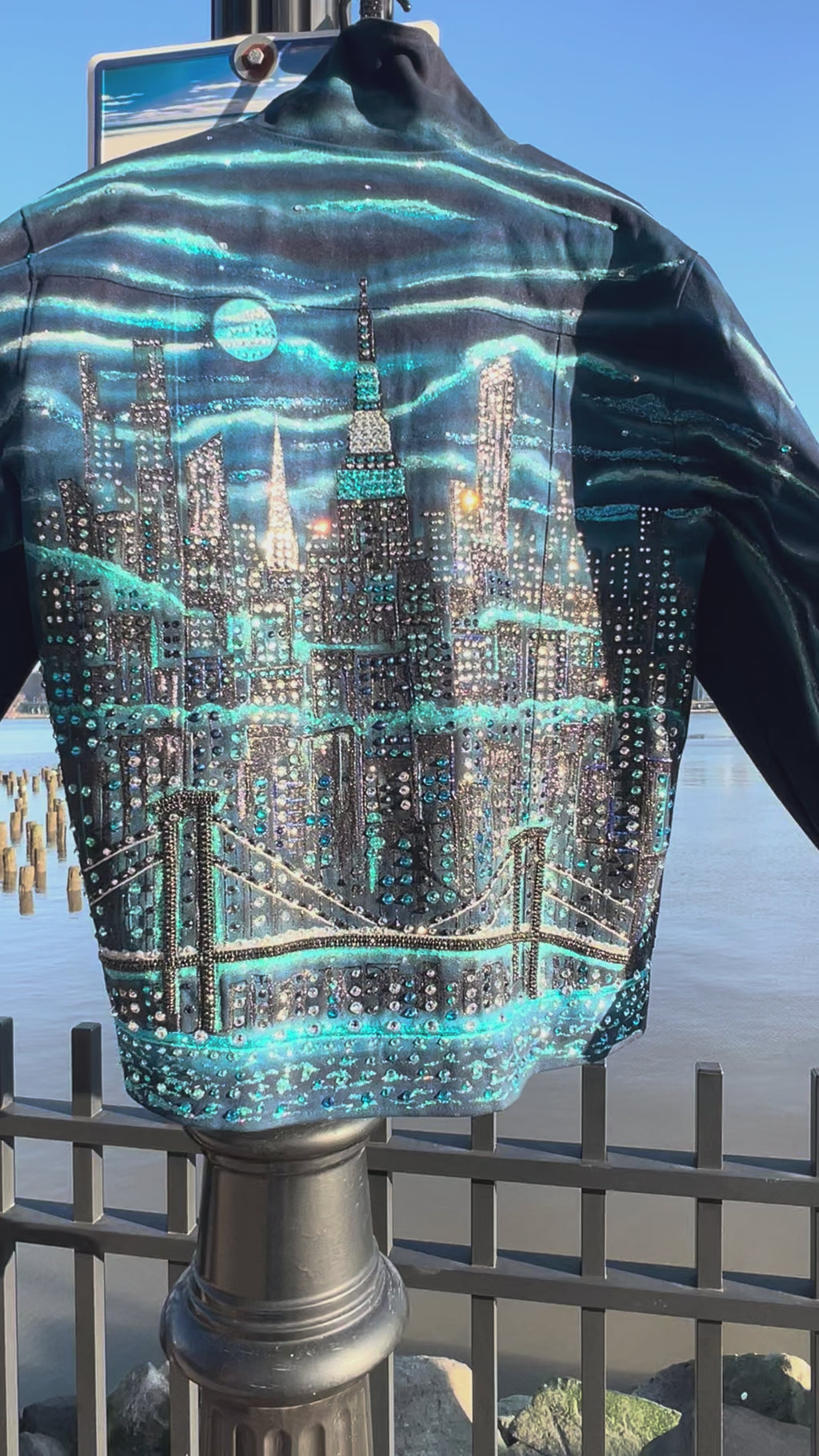 Vertical Video of blue jacket covered in Loria NYC Art with skyline background