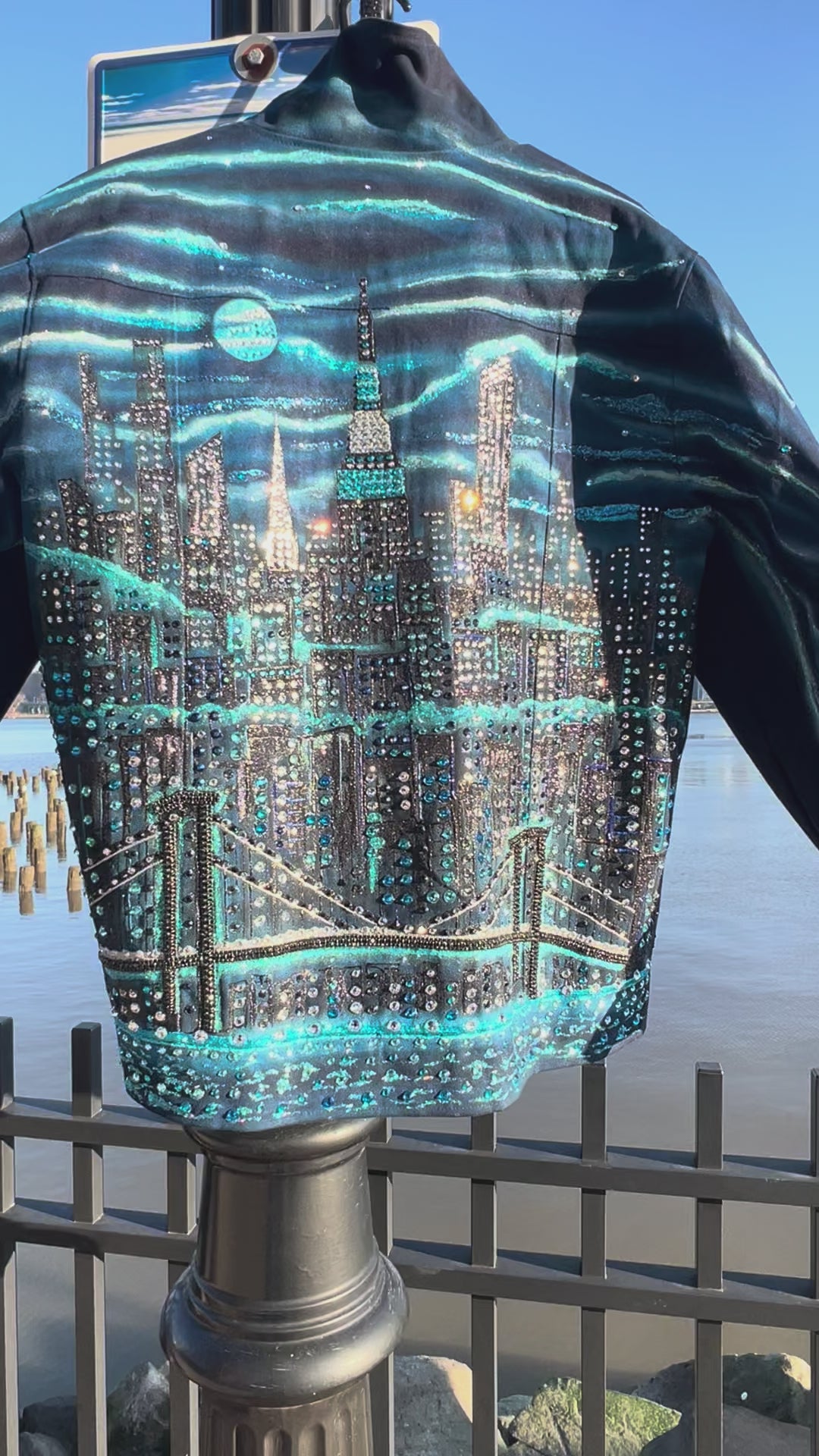 Vertical Video of blue jacket covered in Loria NYC Art with skyline background