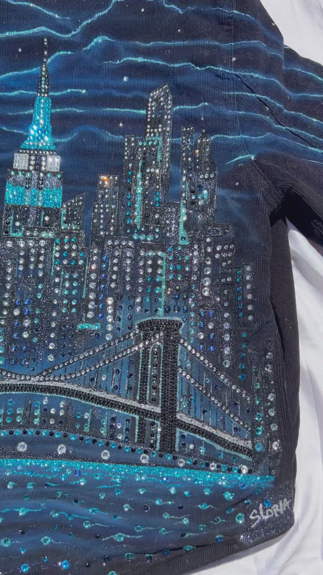 Blue corduroy jacket with Loria NYC Art on back in a video