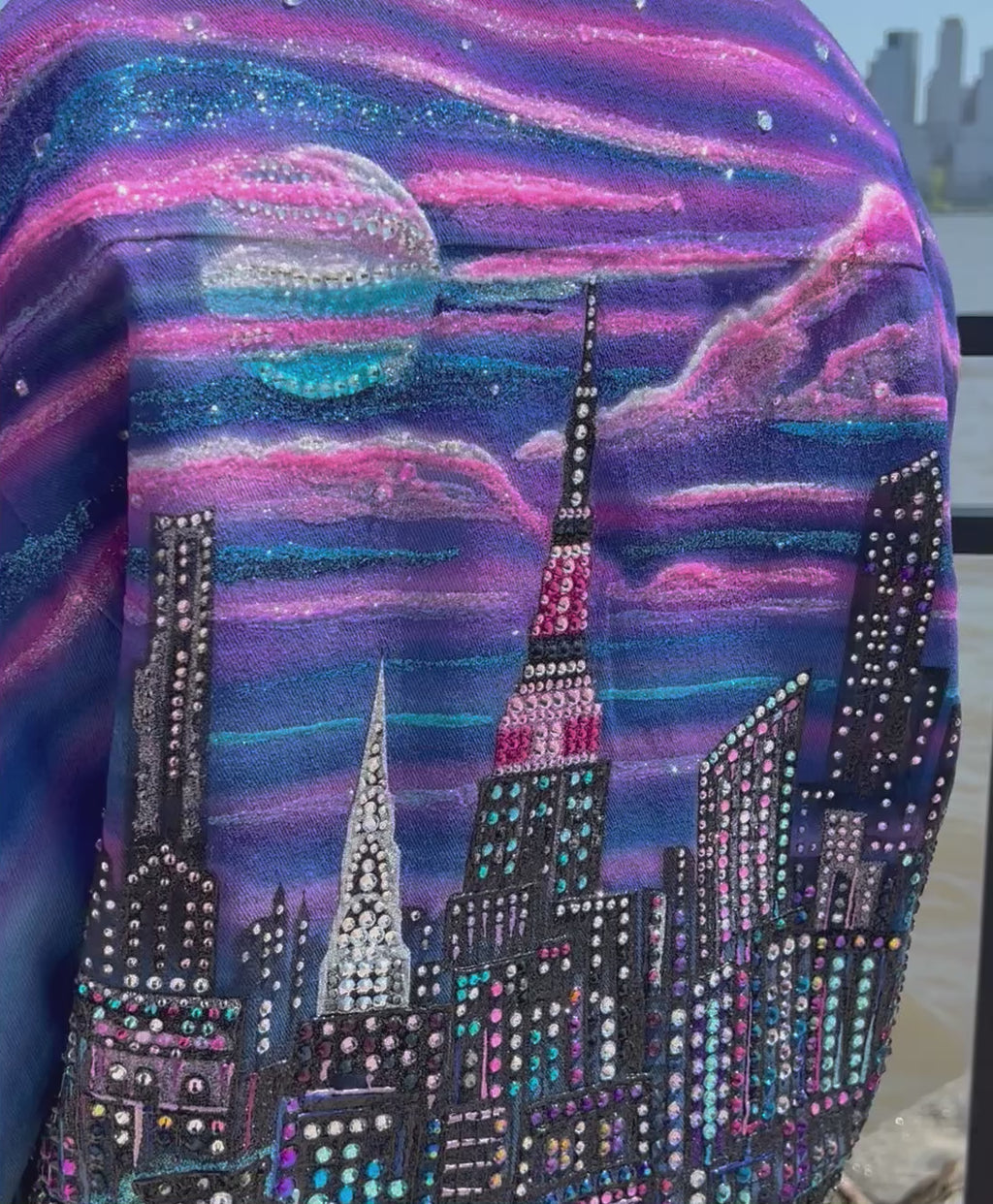 Person posing in a vibrant colorful wearable Loria NYC Art jacket with crystals reflecting in sunlight.