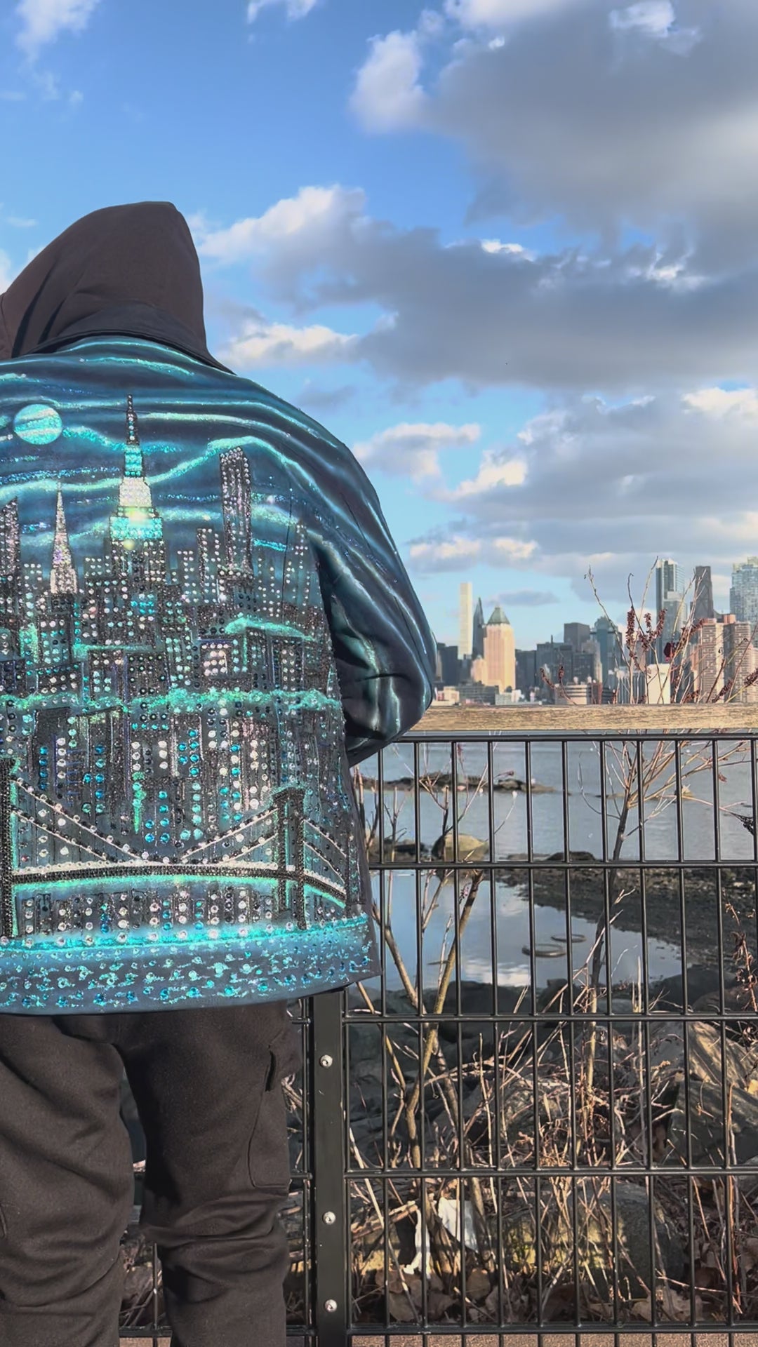 Man wearing  jacket covered in Loria NYC Art with colorful skyline on a sunny day