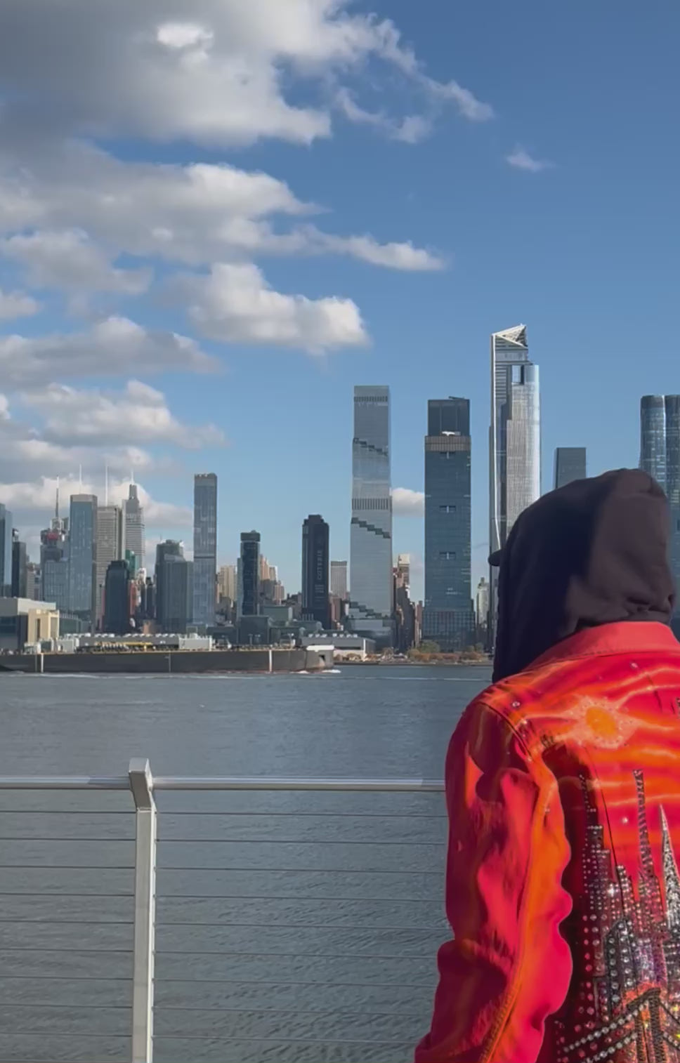 Man looking at the skyline wearing a vibrant orange Loria NYC Art jacket.