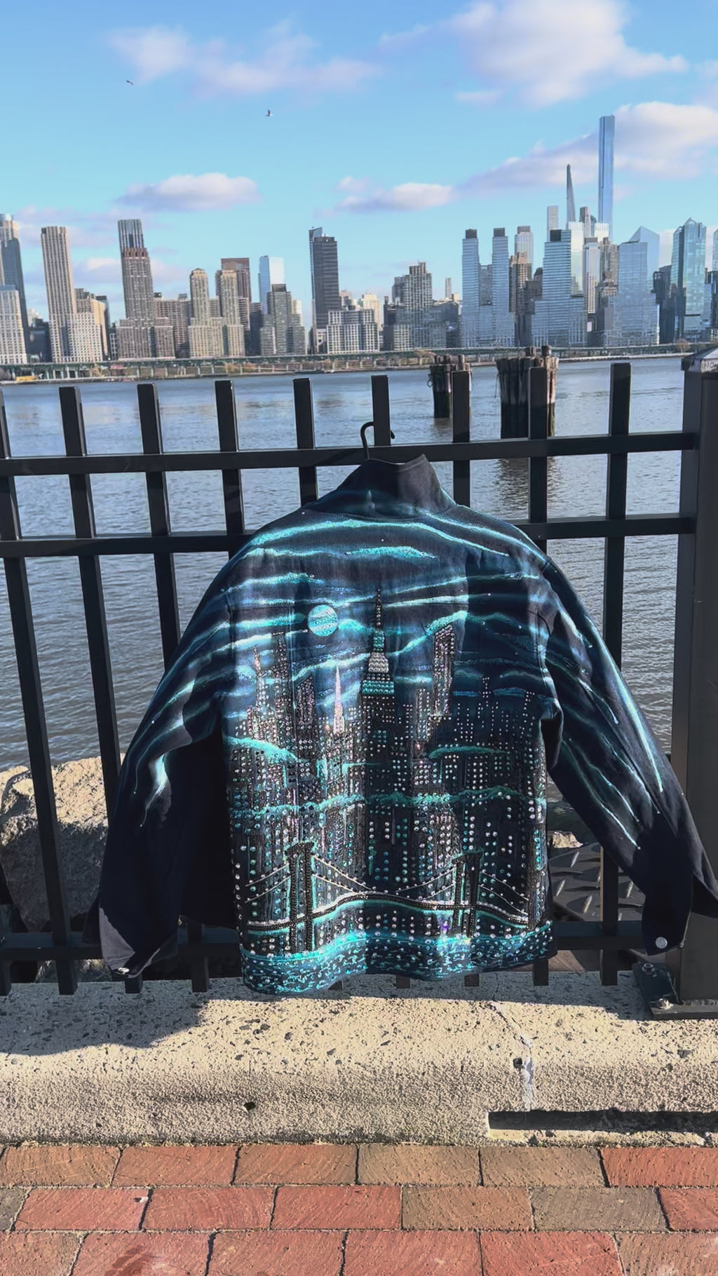 Back of denim jacket covered in Loria NYC Art with colorful skyline on a sunny day