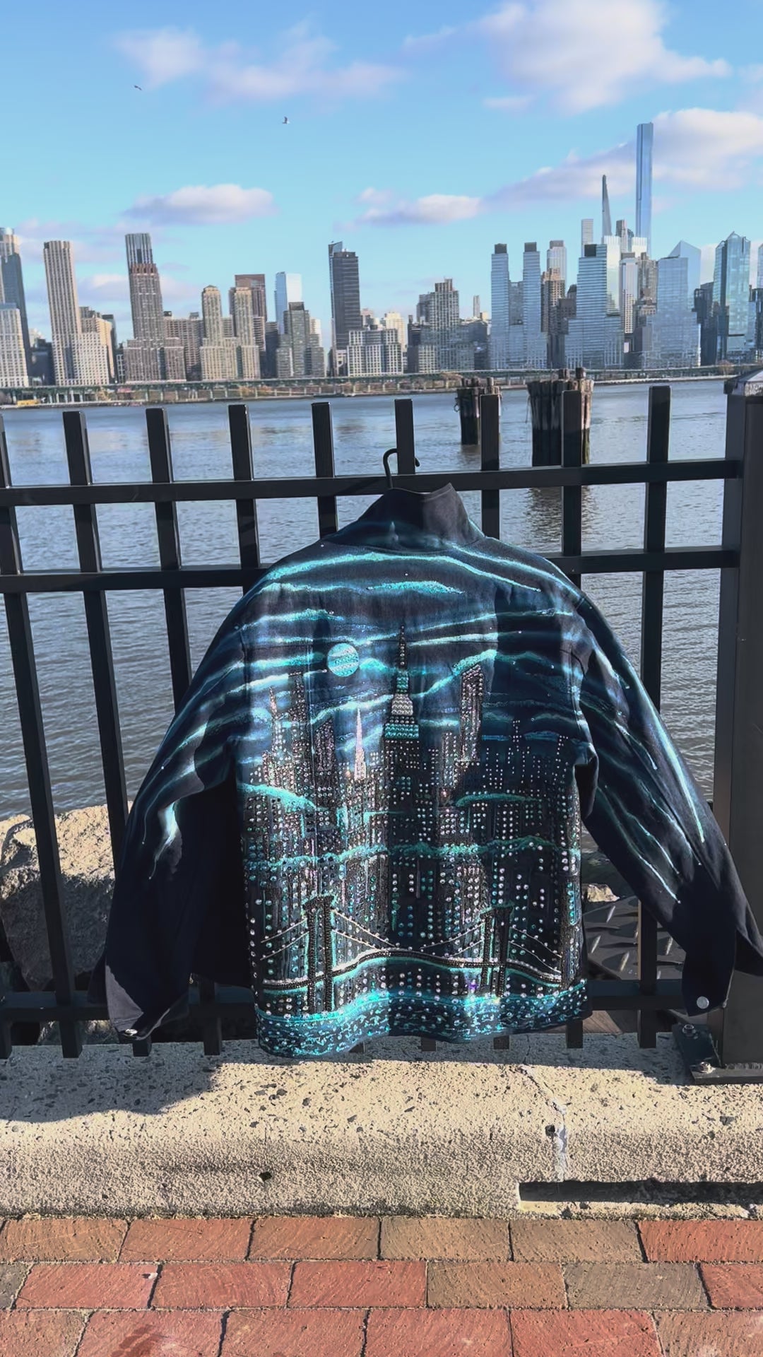 Back of denim jacket covered in Loria NYC Art with colorful skyline on a sunny day
