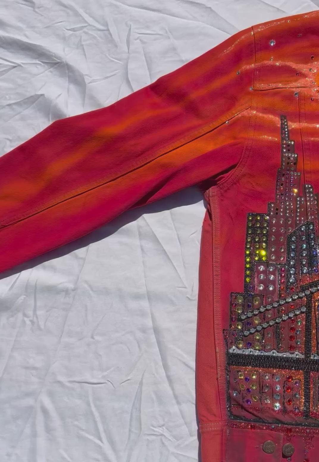 Video of Orange Loria NYC Art jacket with sun reflecting on crystals.